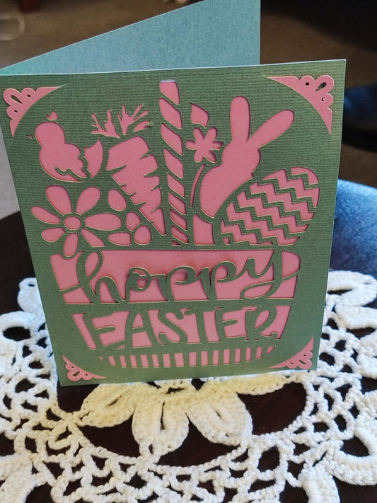 Easter greeting card featuring bunny and floral cut-outs in green and pink, with 'Happy Easter' text.