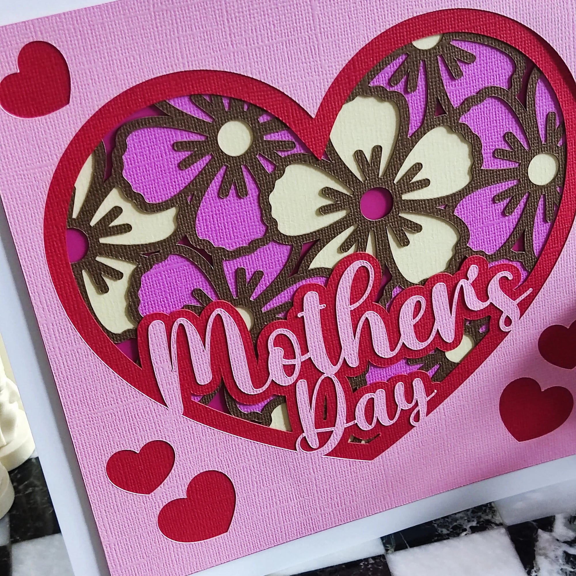 Handmade Mother's Day card with floral heart design in pink and purple, featuring layered cut-out flowers.