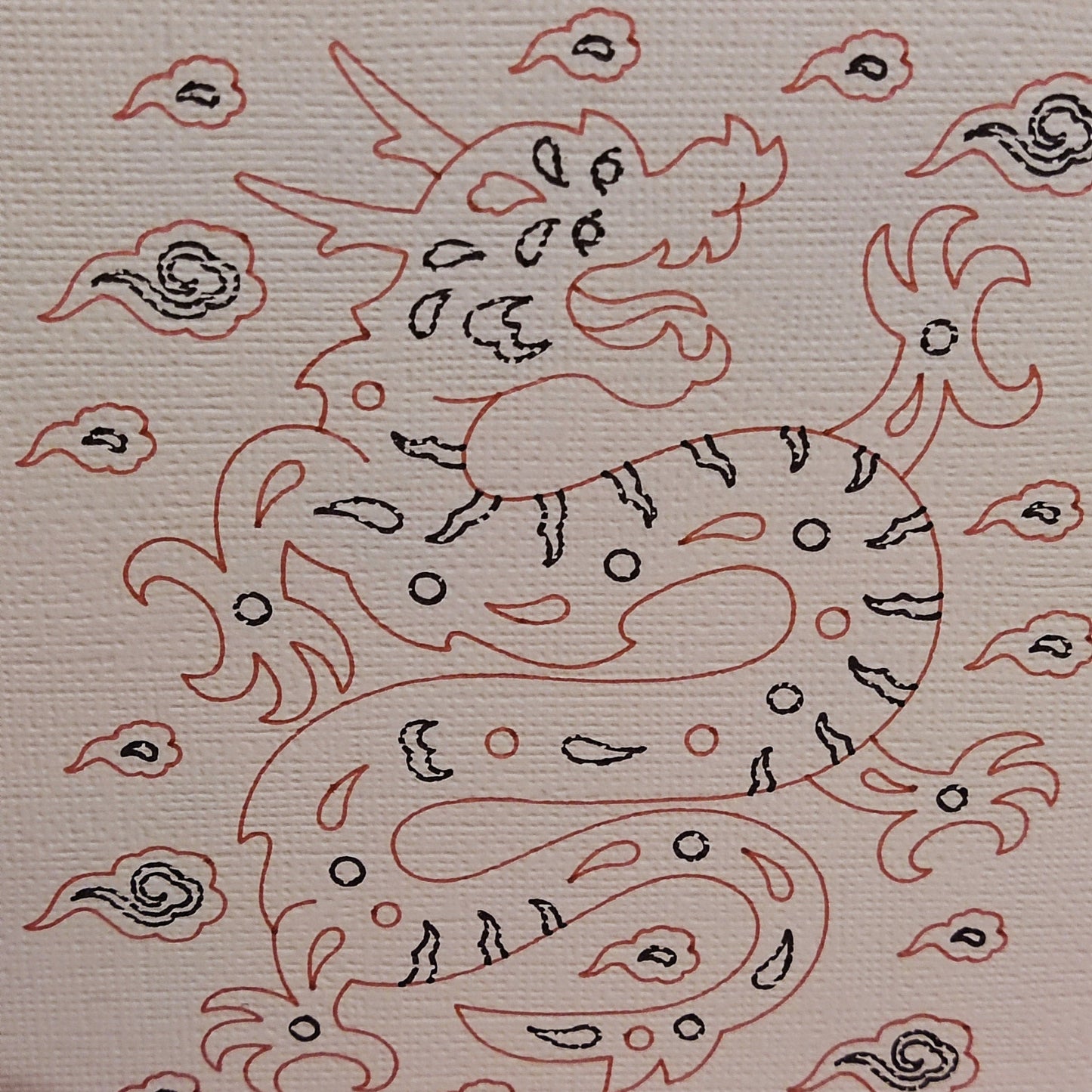 Illustration of a dragon surrounded by clouds, depicted in red and black on textured cardstock.