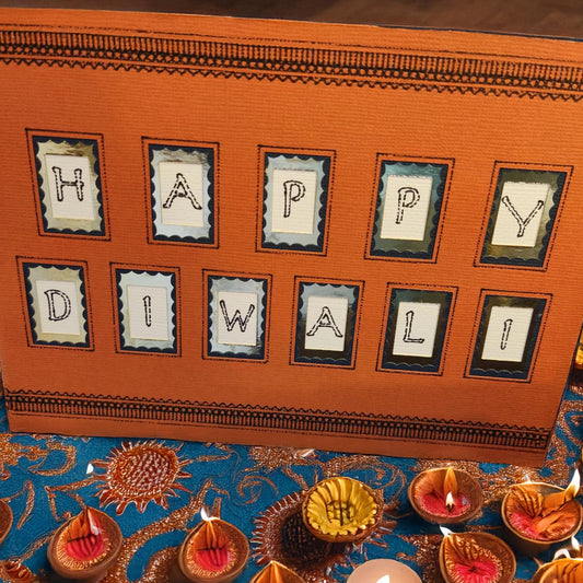 Handmade Happy Diwali card on a colourful table with traditional candles and vibrant decorations.