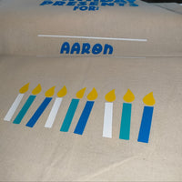 Personalised birthday gift bag with blue and teal candles and yellow flames, name Aaron in blue vinyl on natural cotton sack

