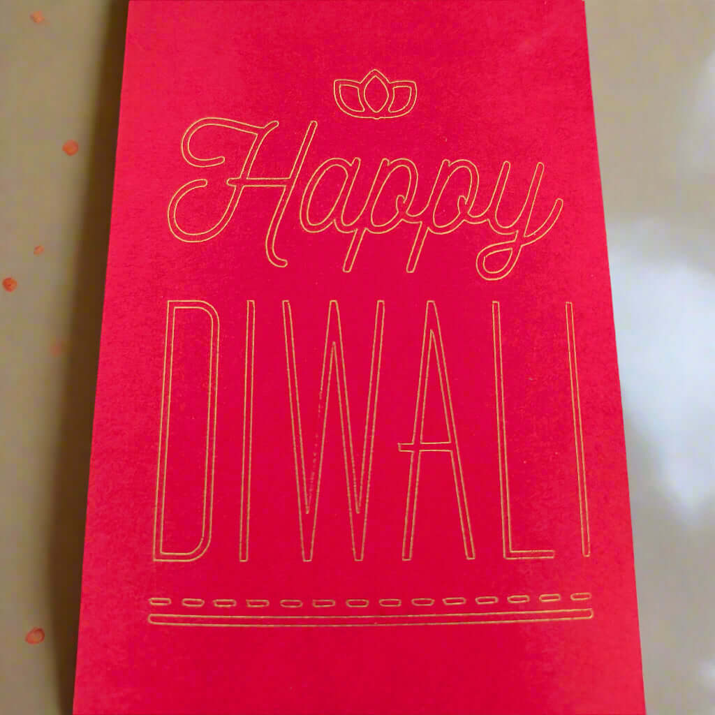 Red Diwali money envelope with gold foil-style text that reads 'Happy Diwali' in elegant lettering, placed on a soft cream and gold-toned background.