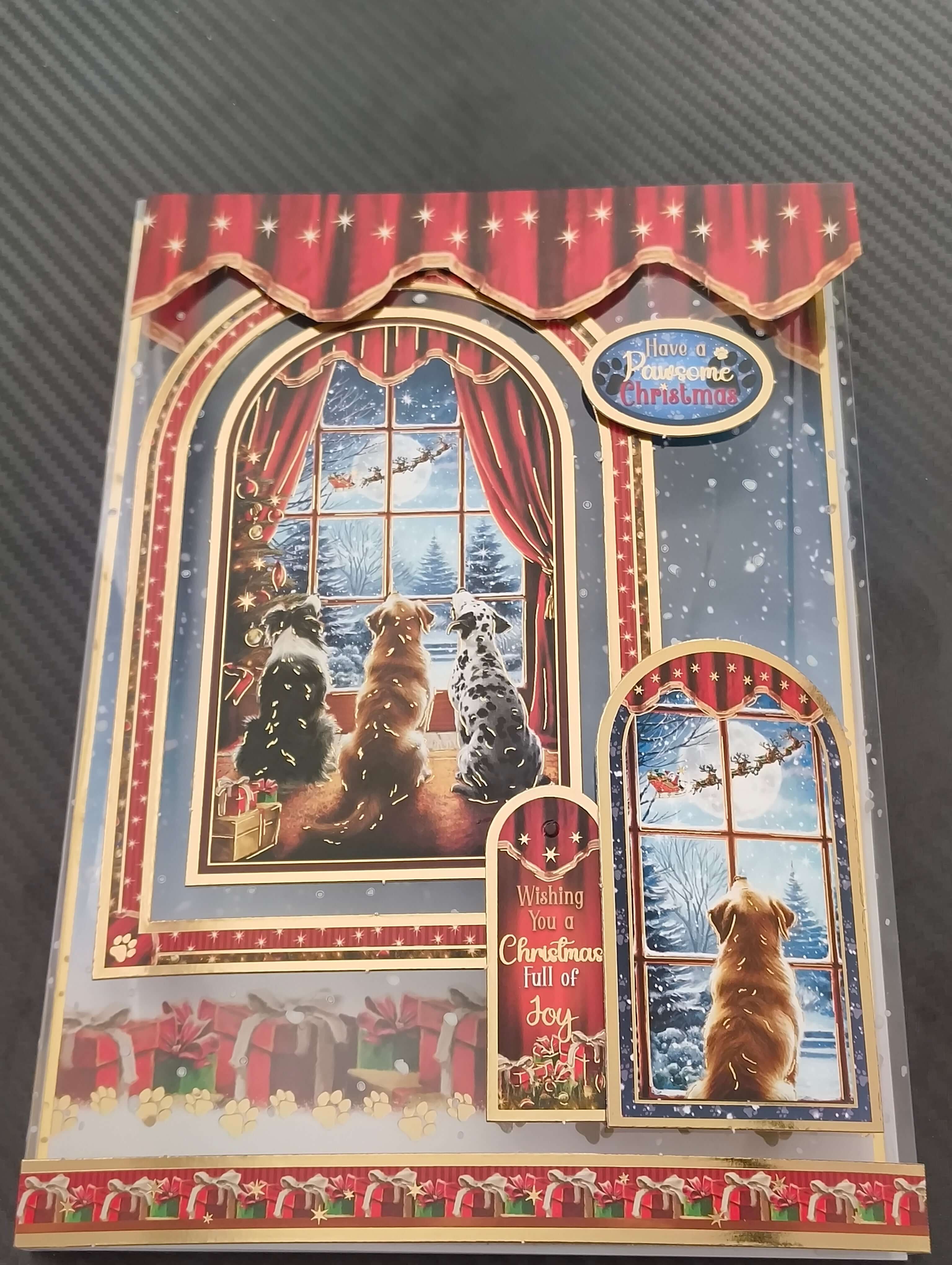 Festive Christmas card featuring three dogs peering out a snowy window with holiday decorations.