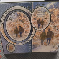 Handmade Christmas card featuring a couple walking with a dog in a snowy landscape, and festive decorations.