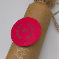 Eco-friendly Christmas crackers with gold holly design and festive pink tag, perfect for the holiday table.