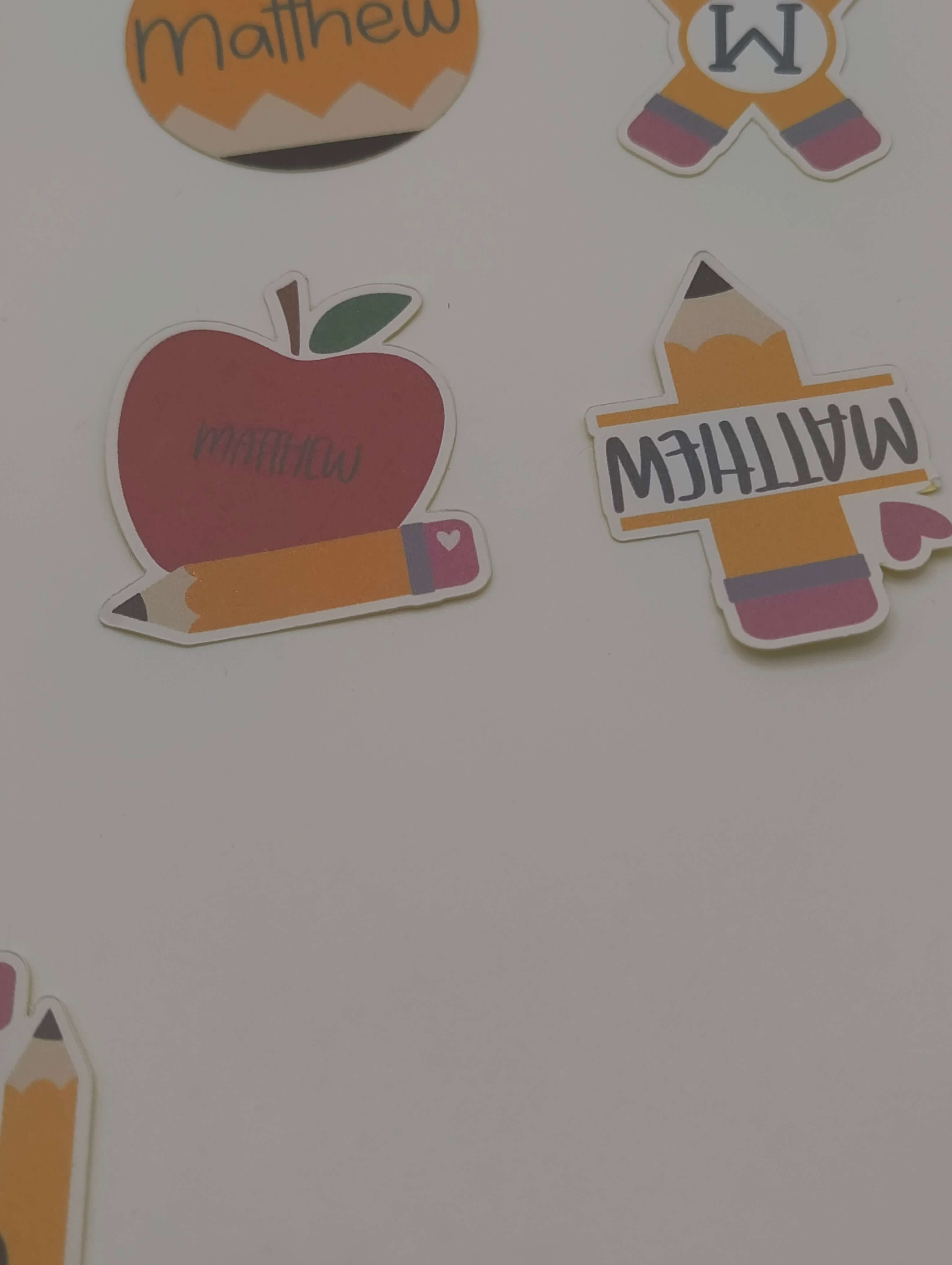 Personalised School Name Stickers showcasing apple, pencil, and name designs for kids' school supplies.