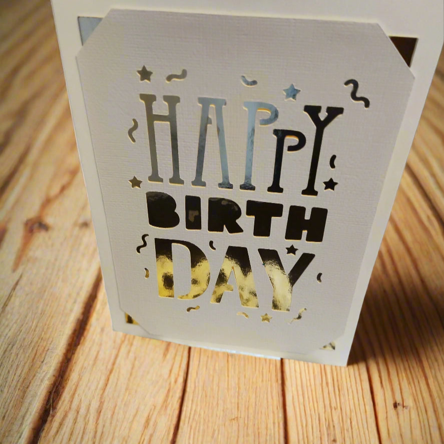 Open laser-cut "Happy Birthday" card holder on a wooden surface.


