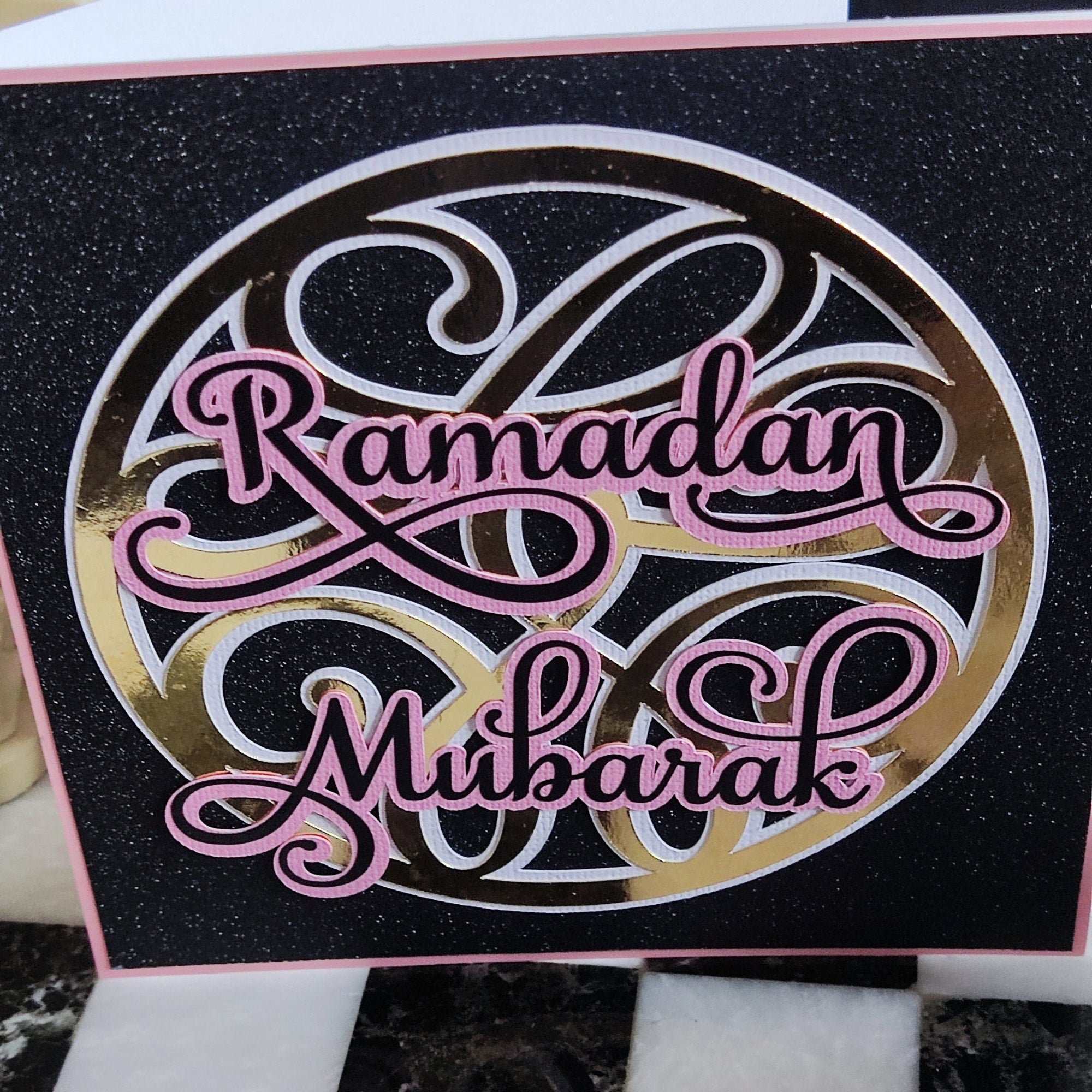 Glittery handmade Ramadan Mubarak card design with elegant pink lettering on a black background.