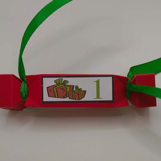 Close-up of red Christmas cracker with green ribbon and festive presents number 1 label