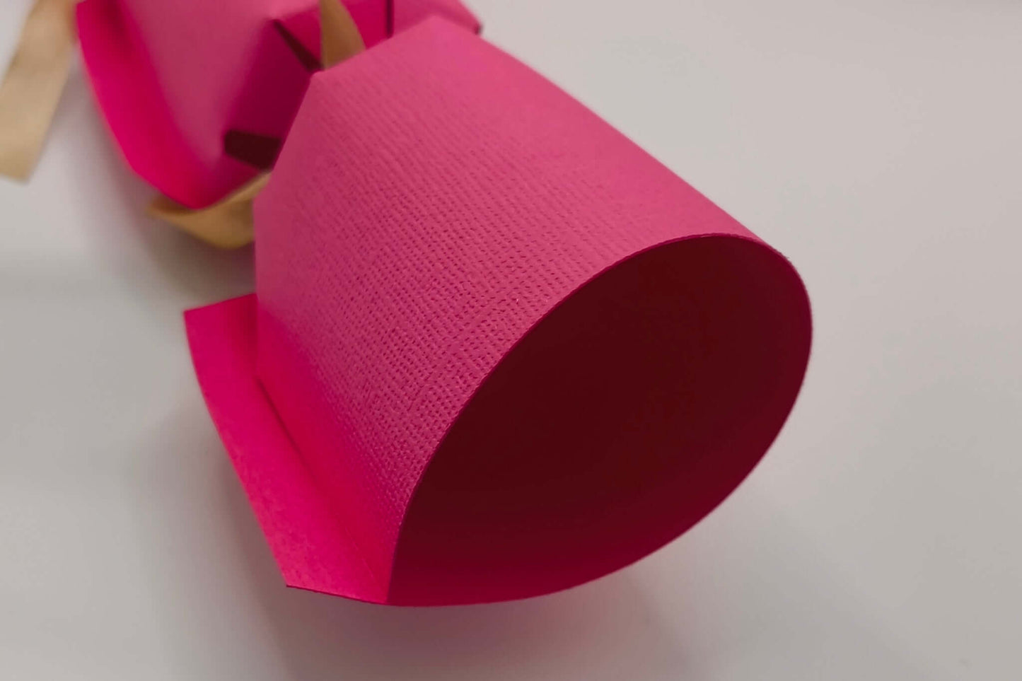 Close-up of a handmade personalised birthday cracker in vibrant pink, showcasing its unique design and texture.