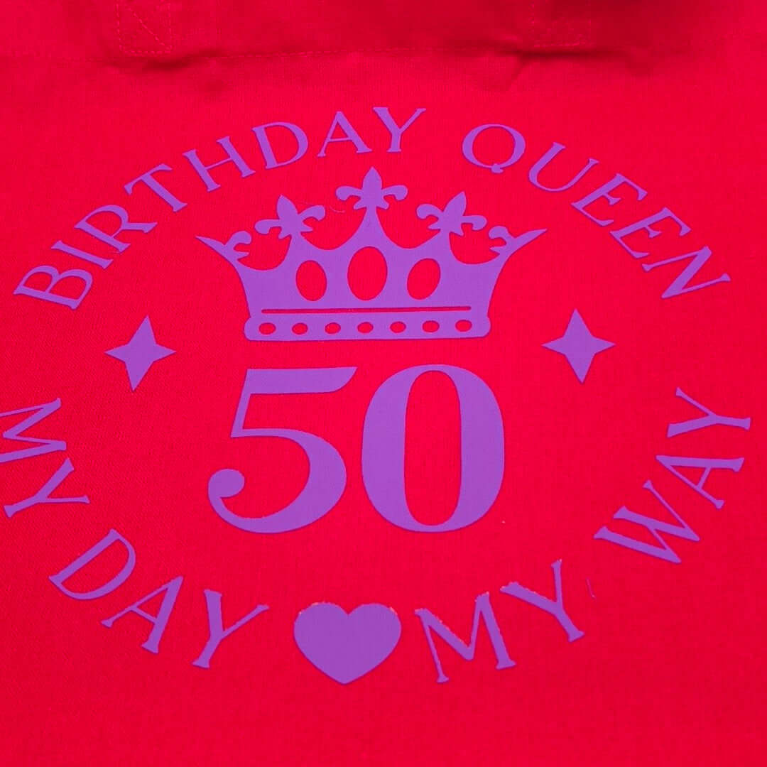Close-up of red tote bag showing purple crown and number 50 with birthday queen slogan.