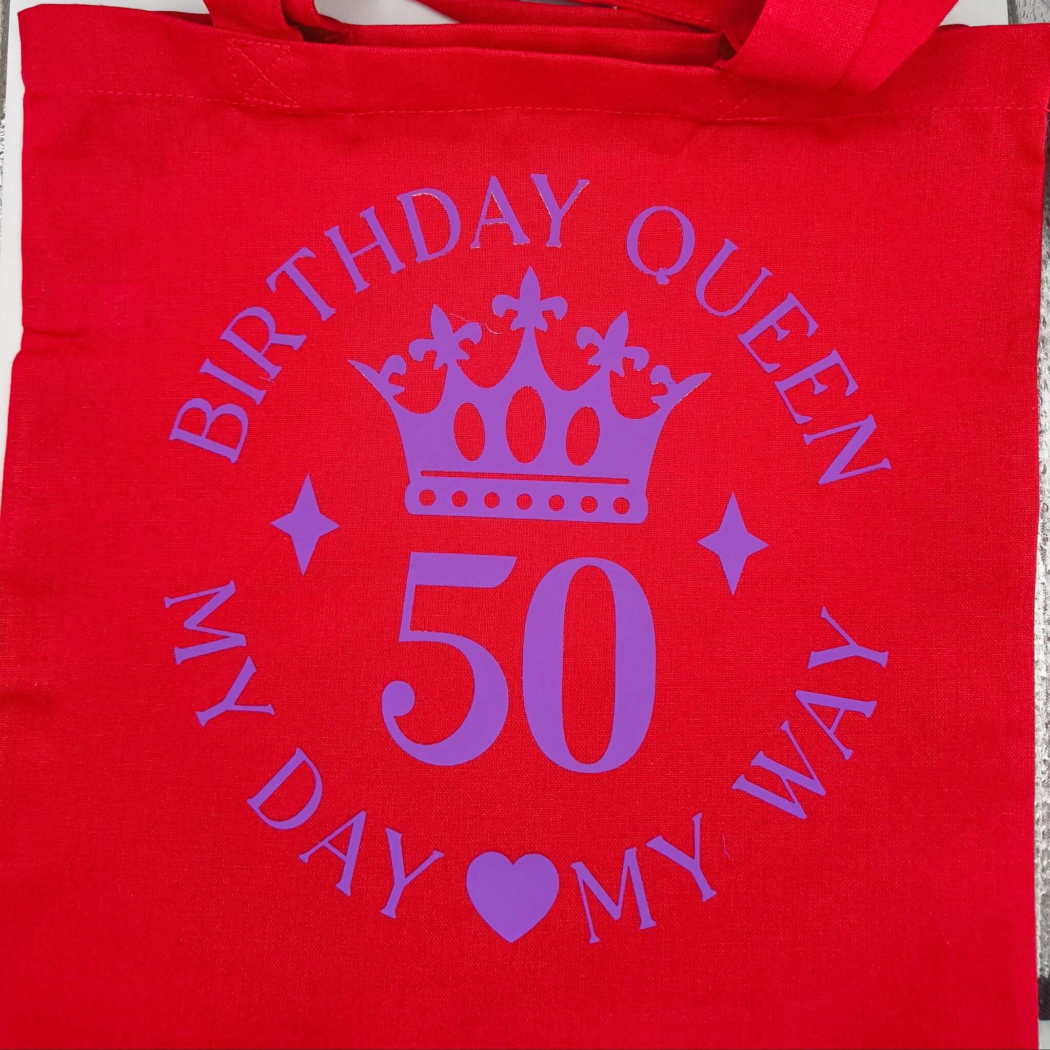 Red birthday queen tote bag laid flat, purple crown design with number 50.