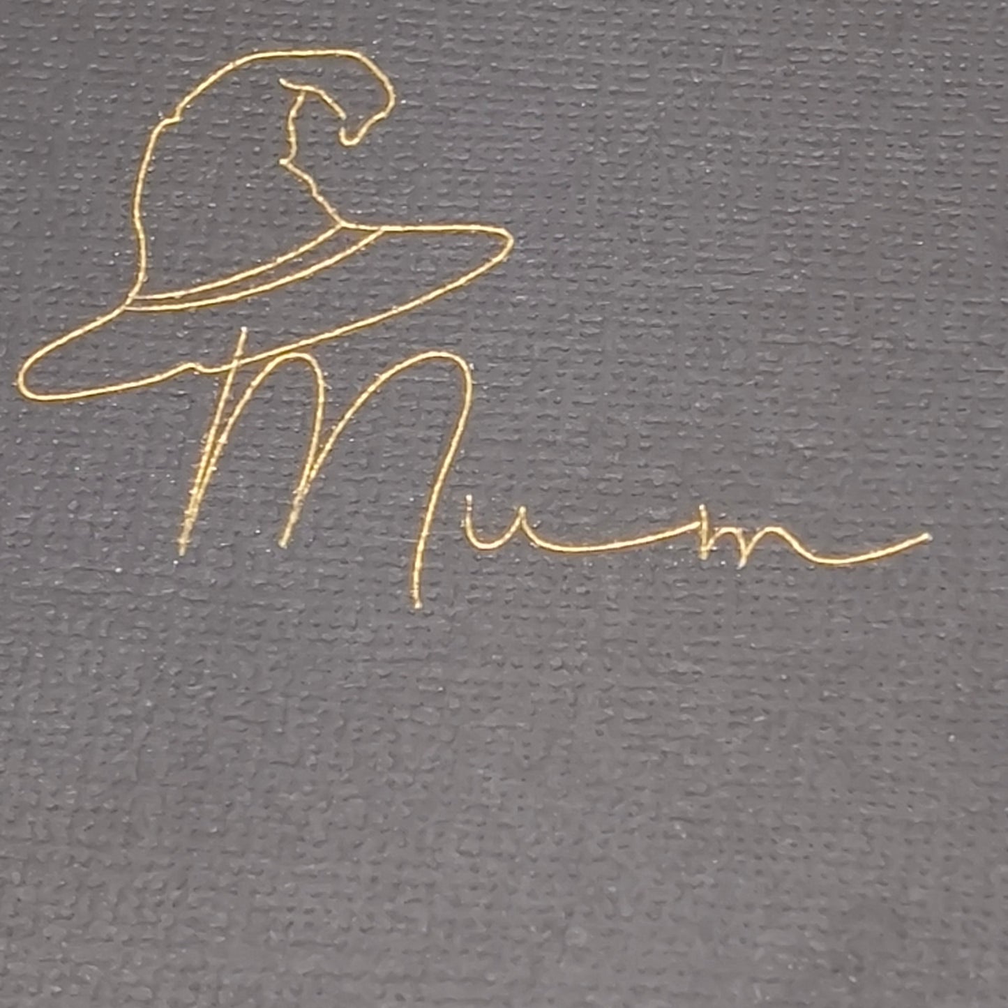 Extreme close-up of gold witch hat and “Mum” wording on black textured cracker card