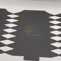 Flat black cracker template with diamond cut-out edges and gold foil witch hat “Mum” design in the centre