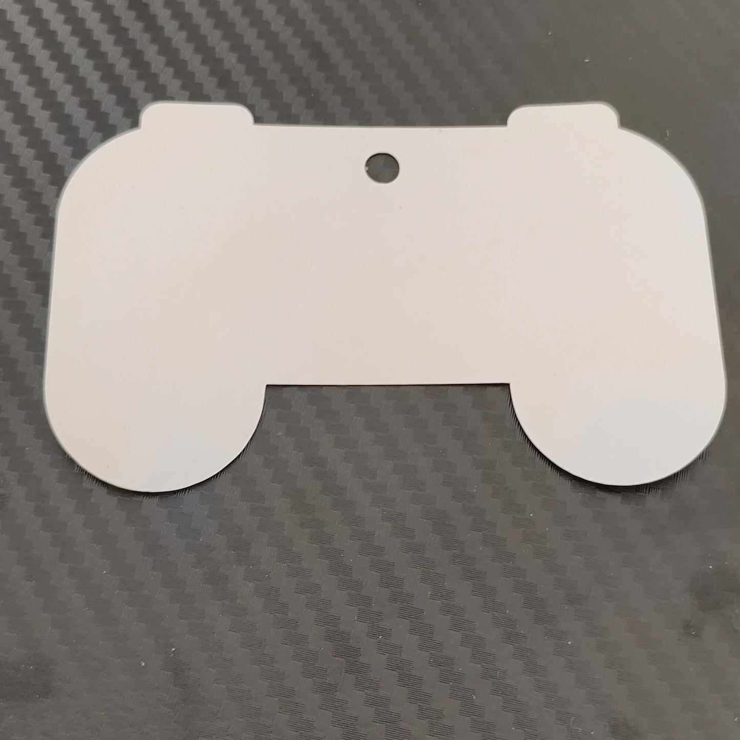 Hollow outline of a gaming controller gift tag on black carbon fiber background for personalized gifts.