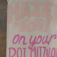 Close-up of a personalized Bat Mitzvah gift bag with pink and blush lettering saying 'Mazel Tov! on your Bat Mitzvah'.