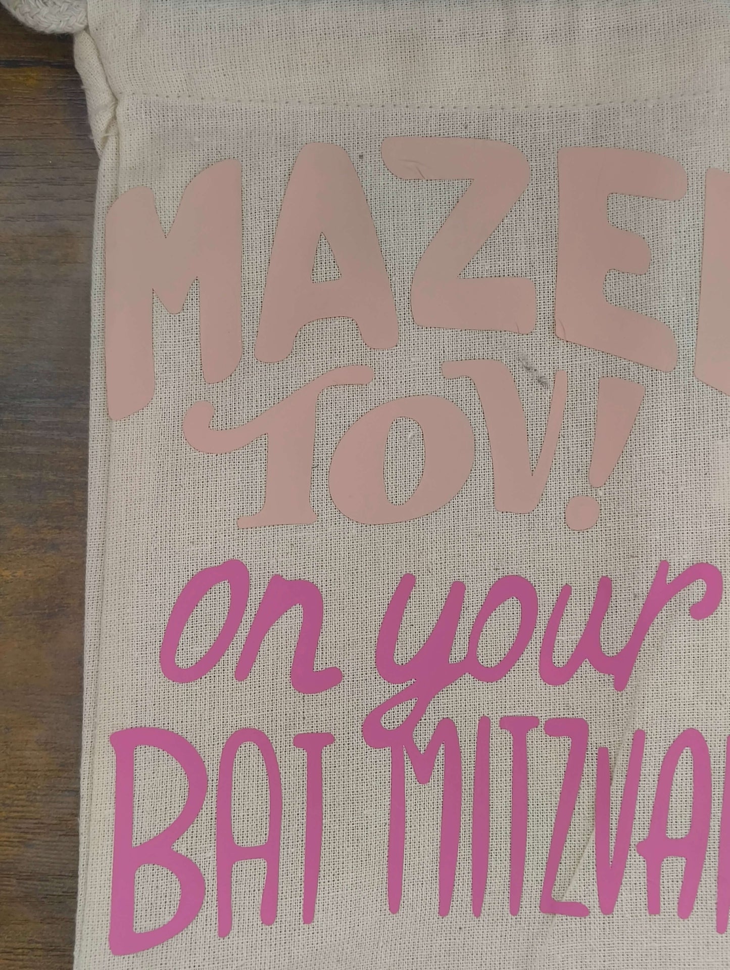 Close-up of a personalized Bat Mitzvah gift bag with pink and blush lettering saying 'Mazel Tov! on your Bat Mitzvah'.
