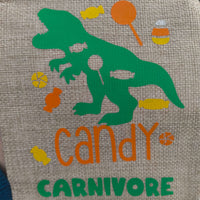 Close-up of a hessian fabric design featuring a green dinosaur silhouette surrounded by colourful sweets and the words 'Candy Carnivore' in orange and green lettering