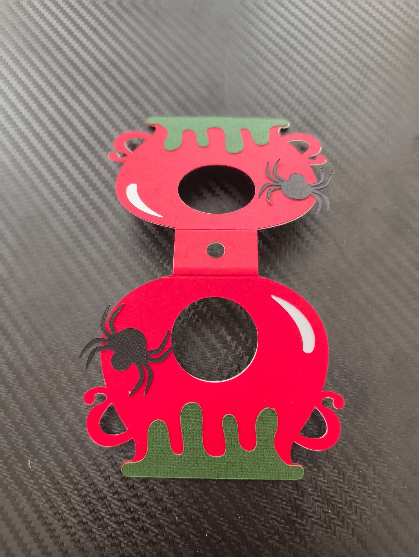 Red and green Halloween lollipop holder designed like a cauldron with spider embellishments.