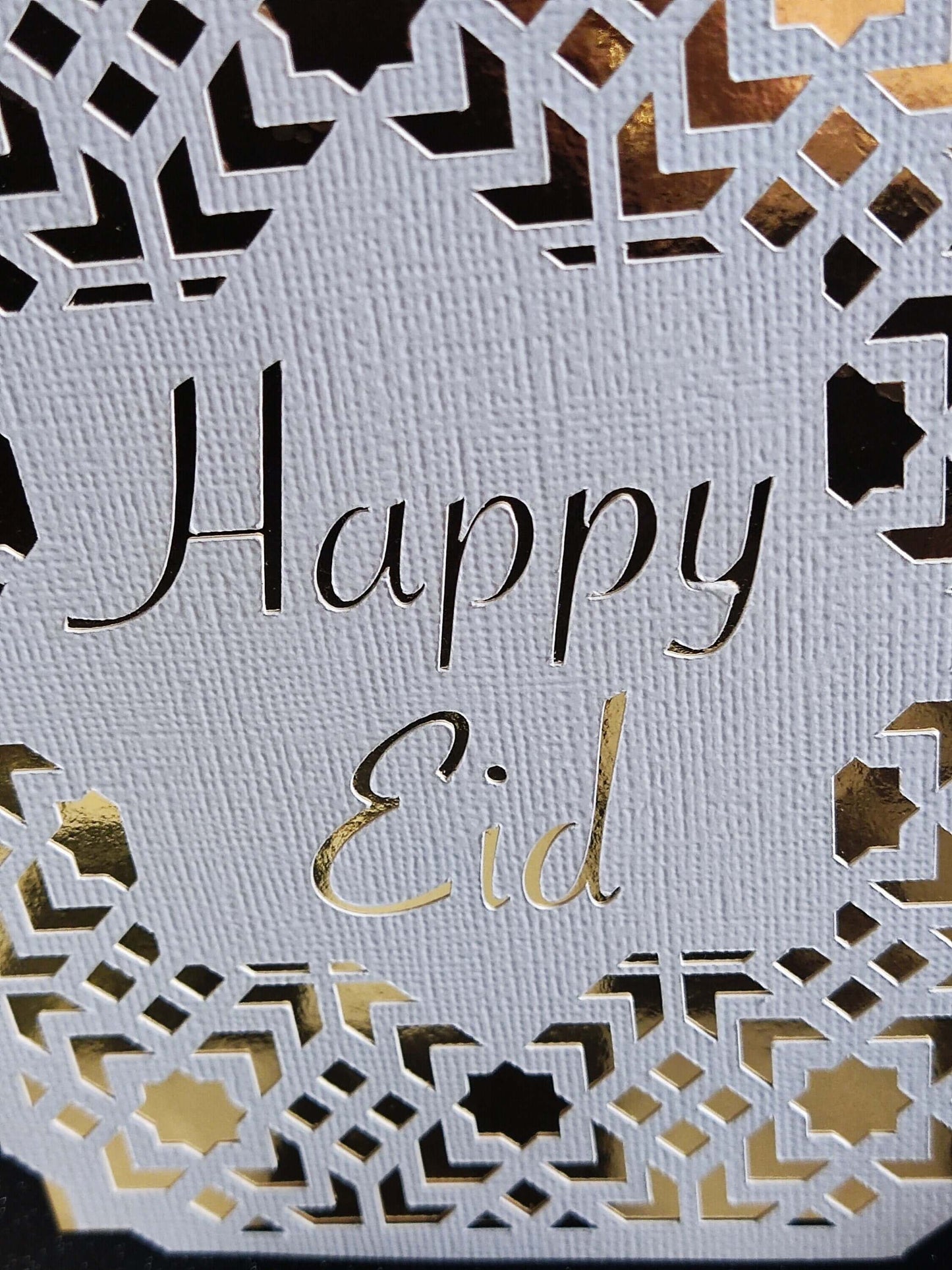 Happy Eid Card featuring intricate laser cut Islamic geometric design in gold and white.