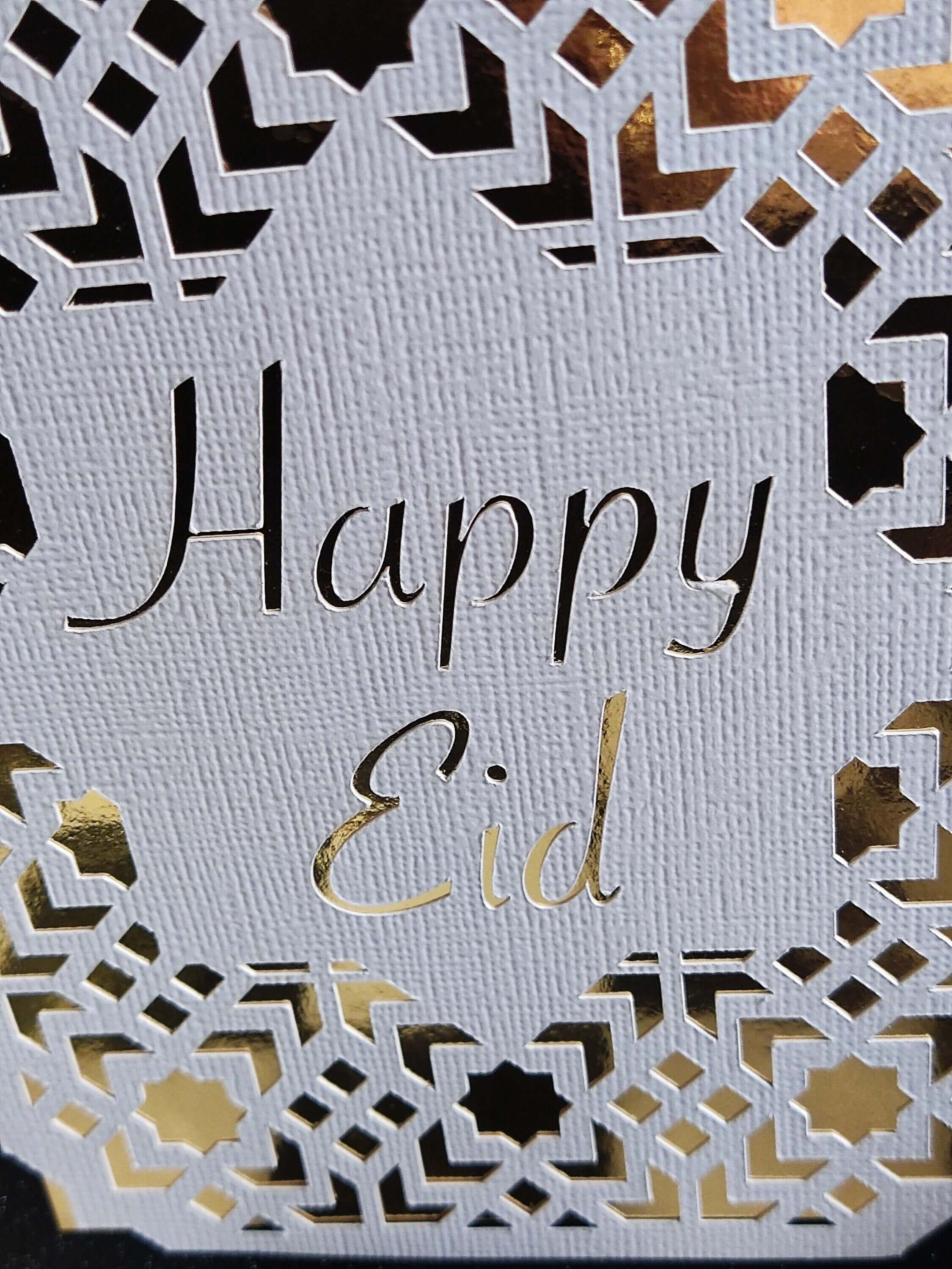 Happy Eid Card featuring intricate laser cut Islamic geometric design in gold and white.