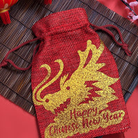 Chinese New Year gift bag in red hessian with glitter gold dragon design, styled with lanterns and blossom decorations.