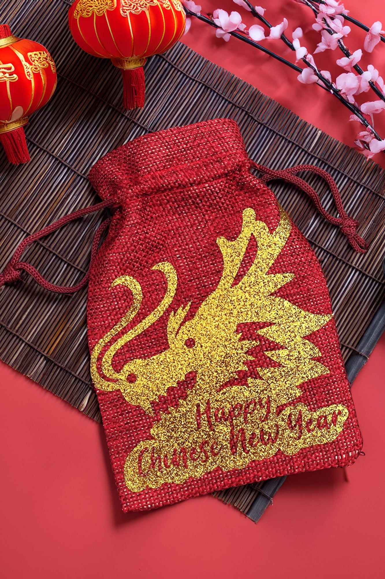 Chinese New Year gift bag in red hessian with glitter gold dragon design, styled with lanterns and blossom decorations.