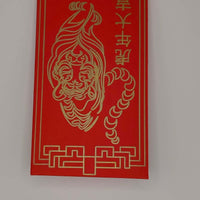 Close-up of red envelope showing tiger face and Chinese characters in gold pen.