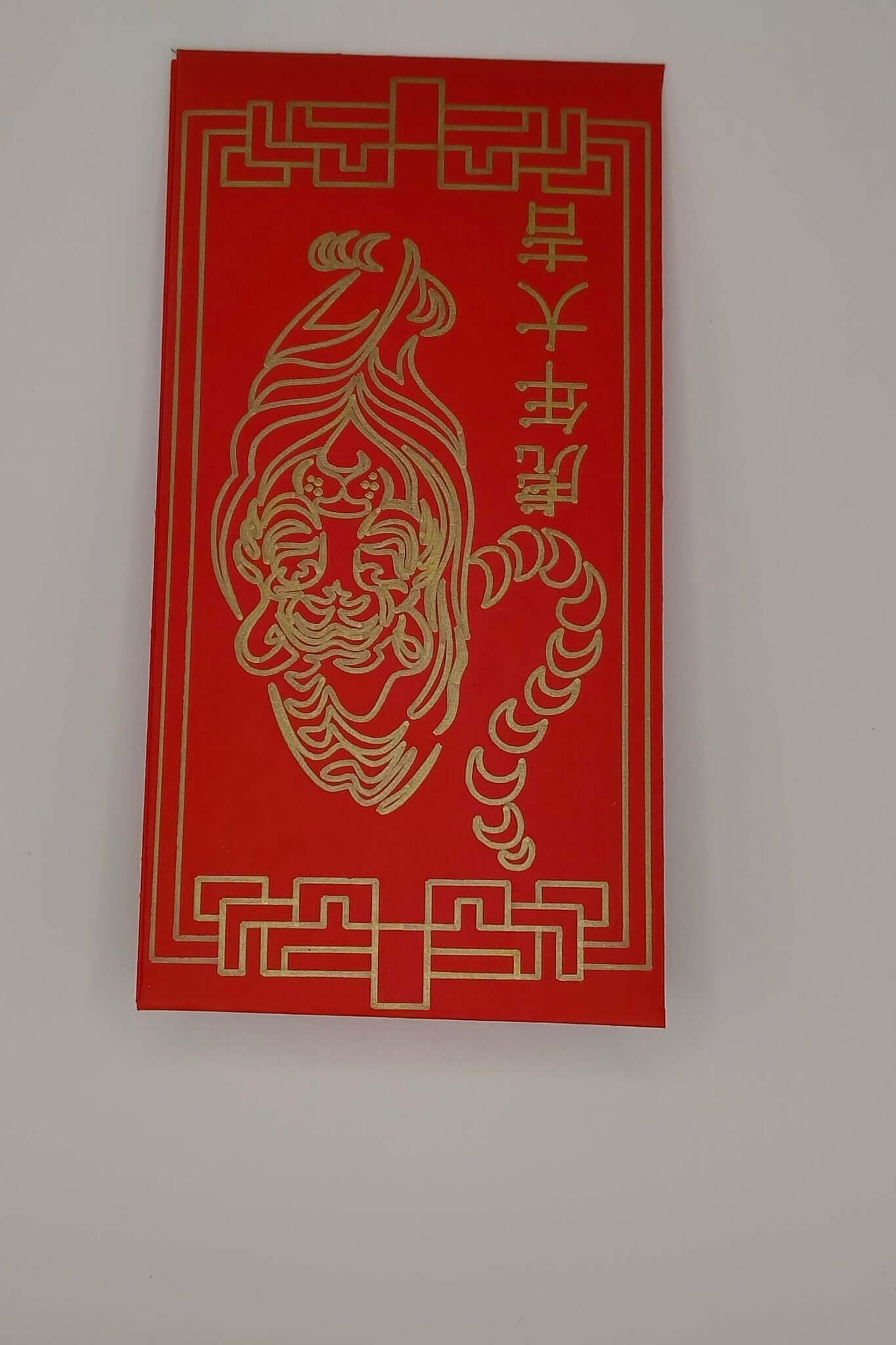 Close-up of red envelope showing tiger face and Chinese characters in gold pen.