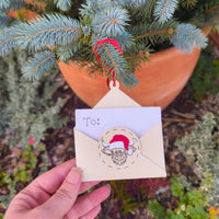 Hand holding Christmas envelope money holder with Santa cow design near pine tree