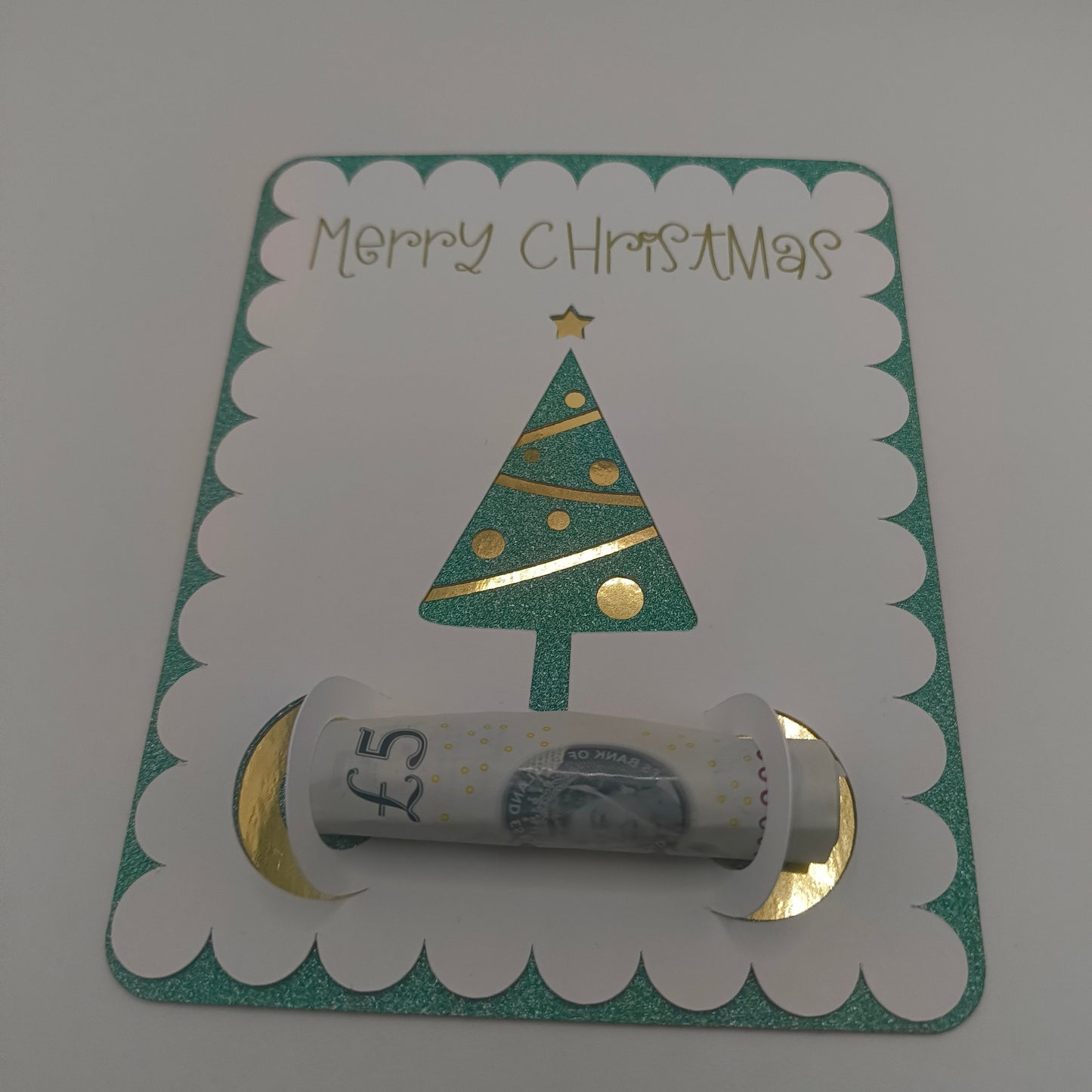 Handmade Christmas money holder card with green glitter border and gold foil Christmas tree, holding a £5 note.