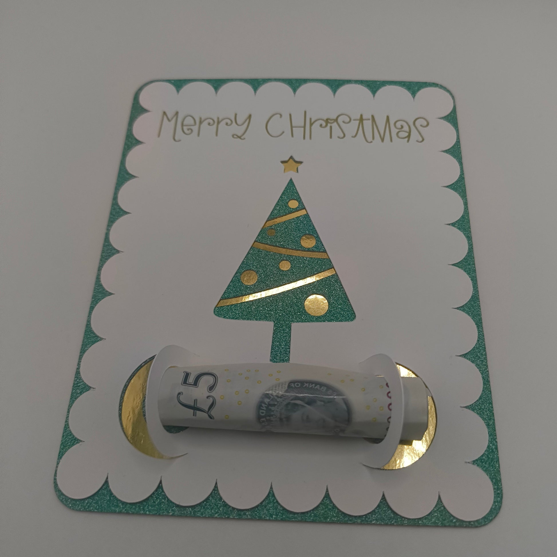 Handmade Christmas money holder card with green glitter border and gold foil Christmas tree, holding a £5 note.