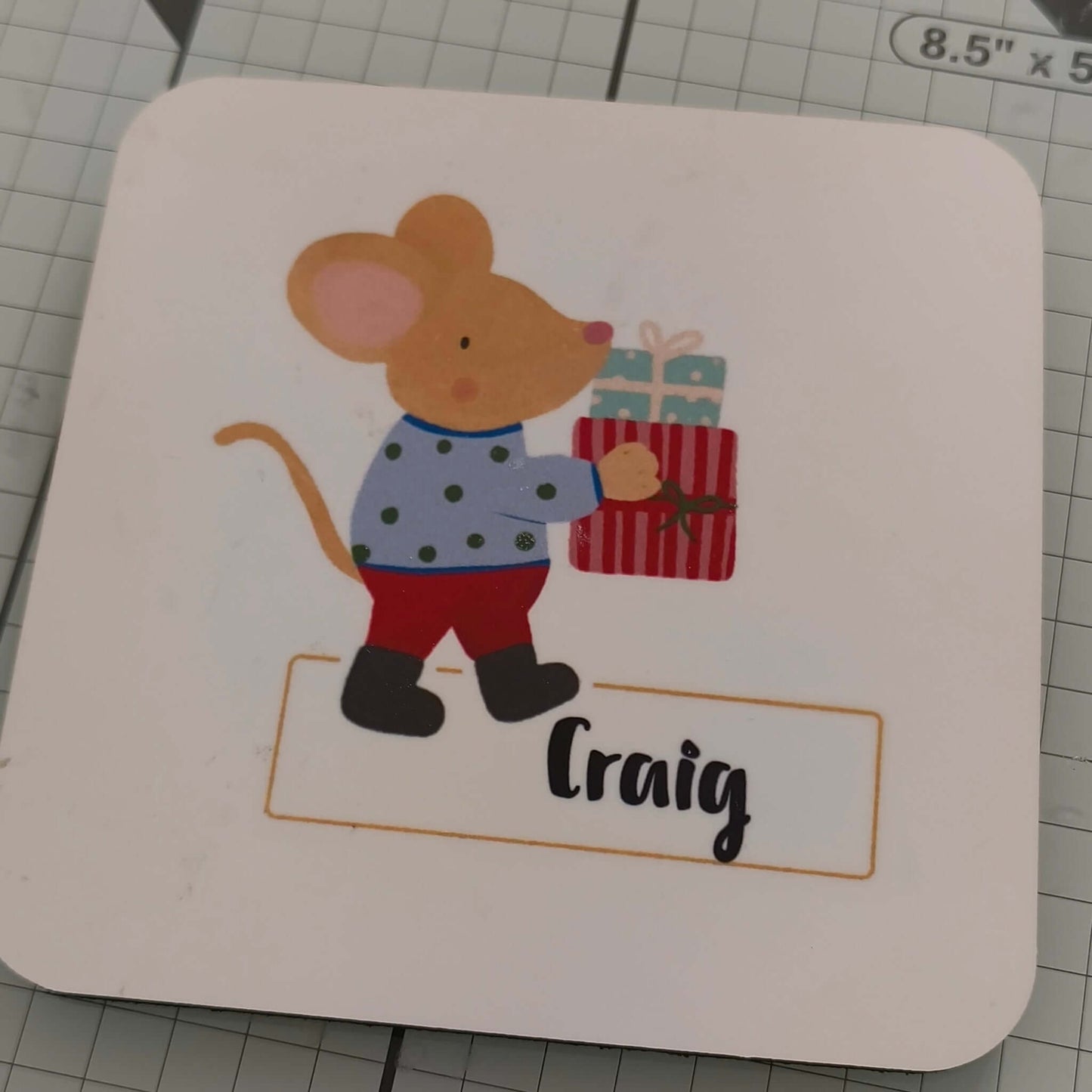 Personalised Christmas Mouse Coaster featuring a cute mouse holding a gift, customized with the name Craig.