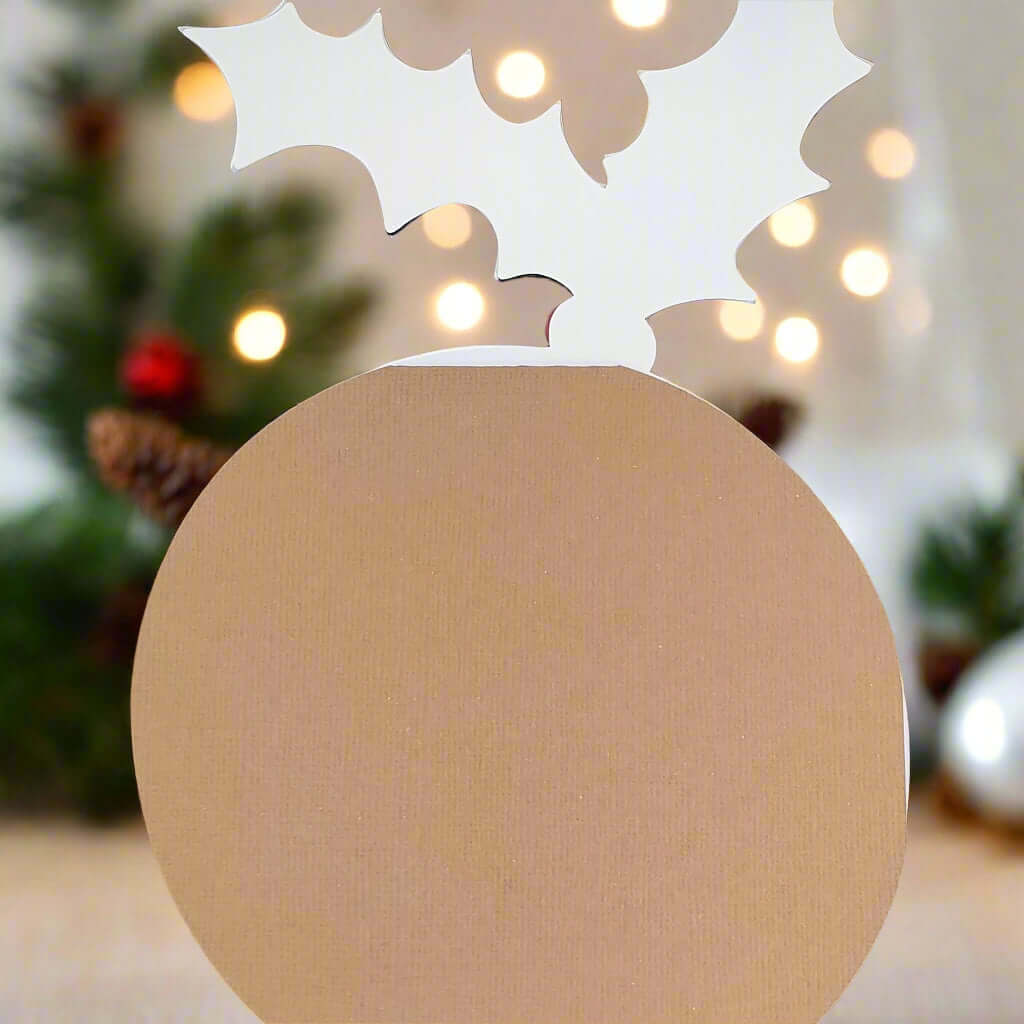 Back view of Christmas pudding-shaped place card, showing plain brown textured cardstock with white holly outline at the top, designed for standing upright on festive tables.