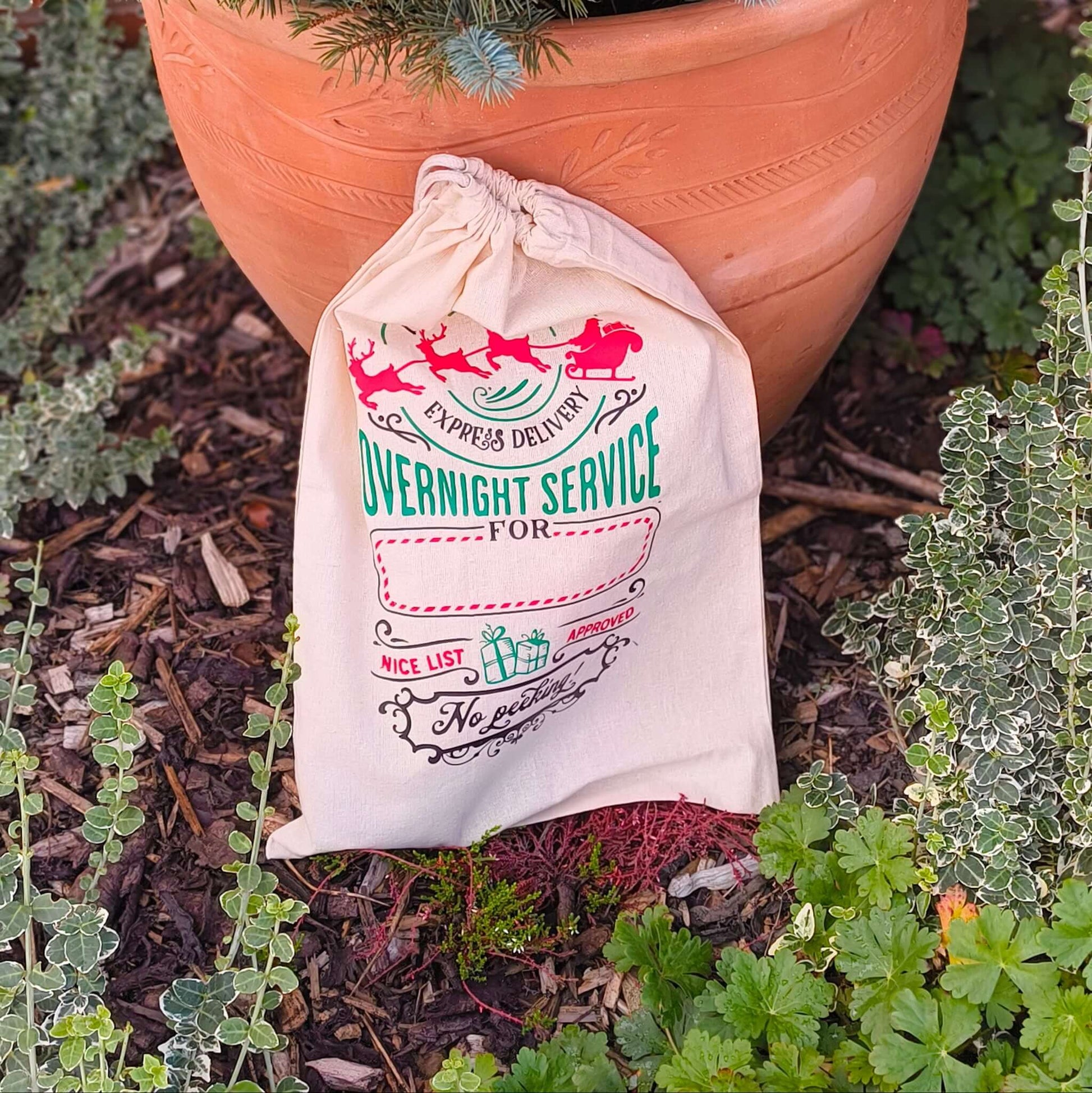 Christmas hessian Santa sack with red and green overnight service design under festive tree
