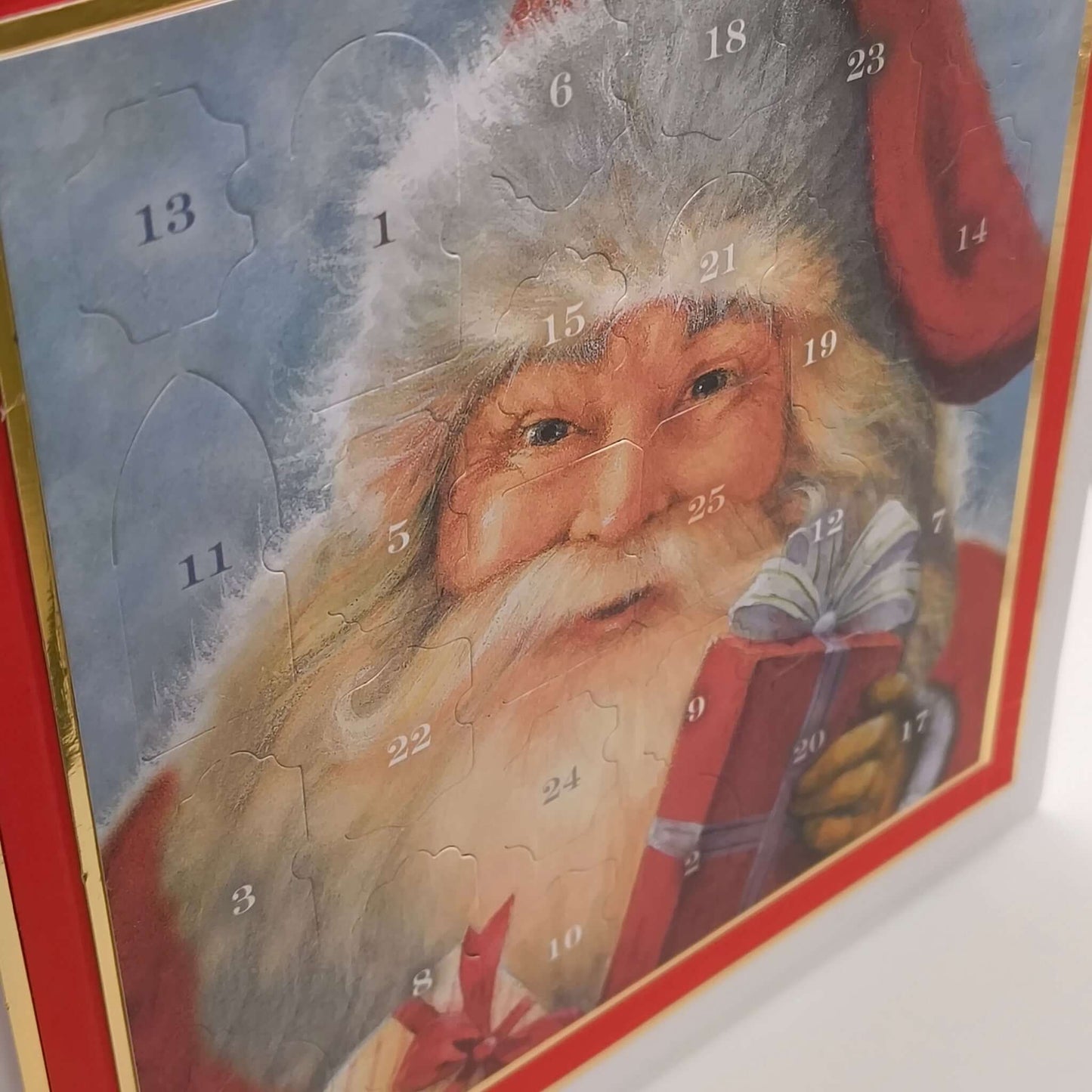 Close-up angled shot of the classic Santa Claus Advent Calendar, highlighting the numbered doors and festive red and gold details on a white background.