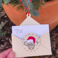 Close-up of handmade Christmas money holder envelope with red Santa hat cow design