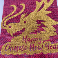 Close-up of glitter gold dragon design with “Happy Chinese New Year” text on red hessian bag.