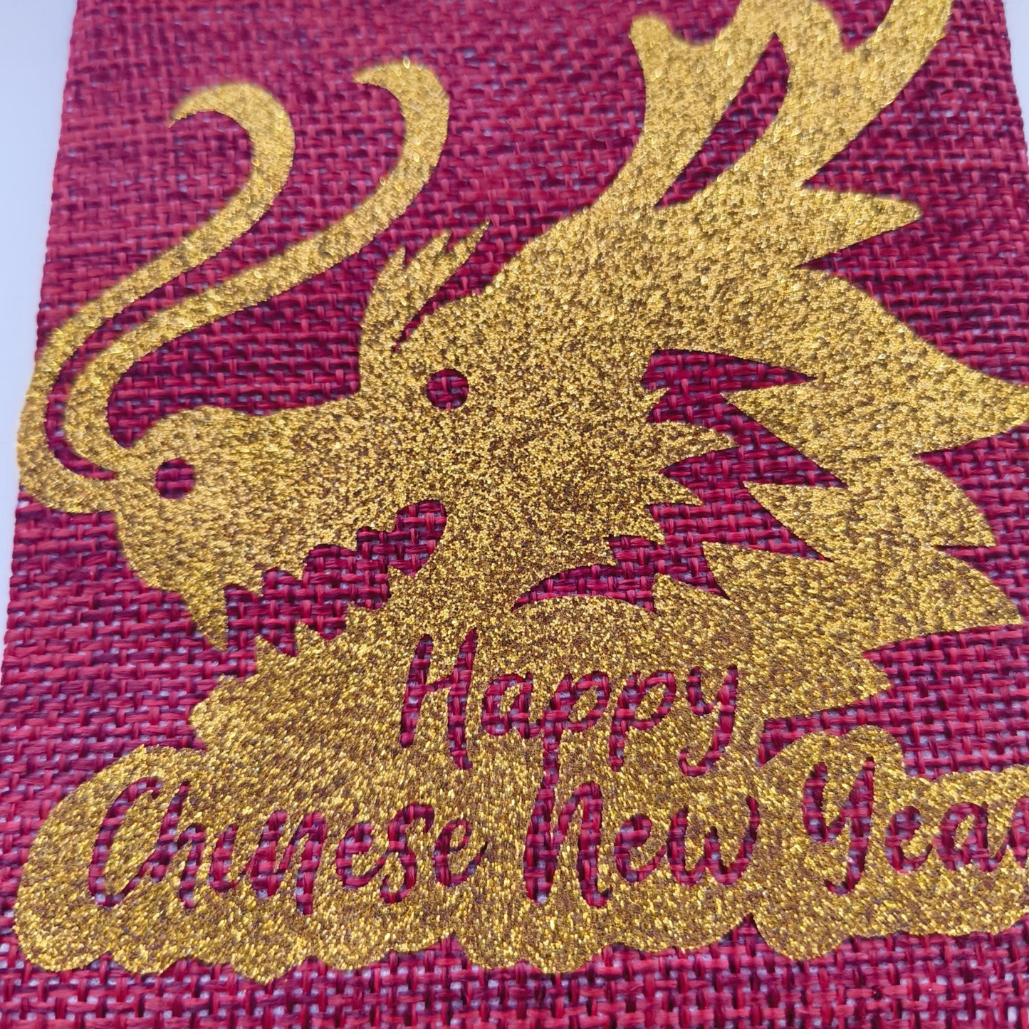 Close-up of glitter gold dragon design with “Happy Chinese New Year” text on red hessian bag.