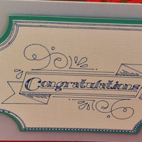 Close-up of the ornate banner design with “Congratulations” text, printed in blue on textured ivory card with a teal border. Highlights the intricate detail of the handmade finish.