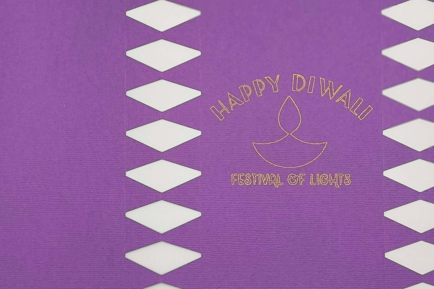 Purple cracker panel close-up showing gold foiled diya symbol with “Happy Diwali Festival of Lights” lettering.