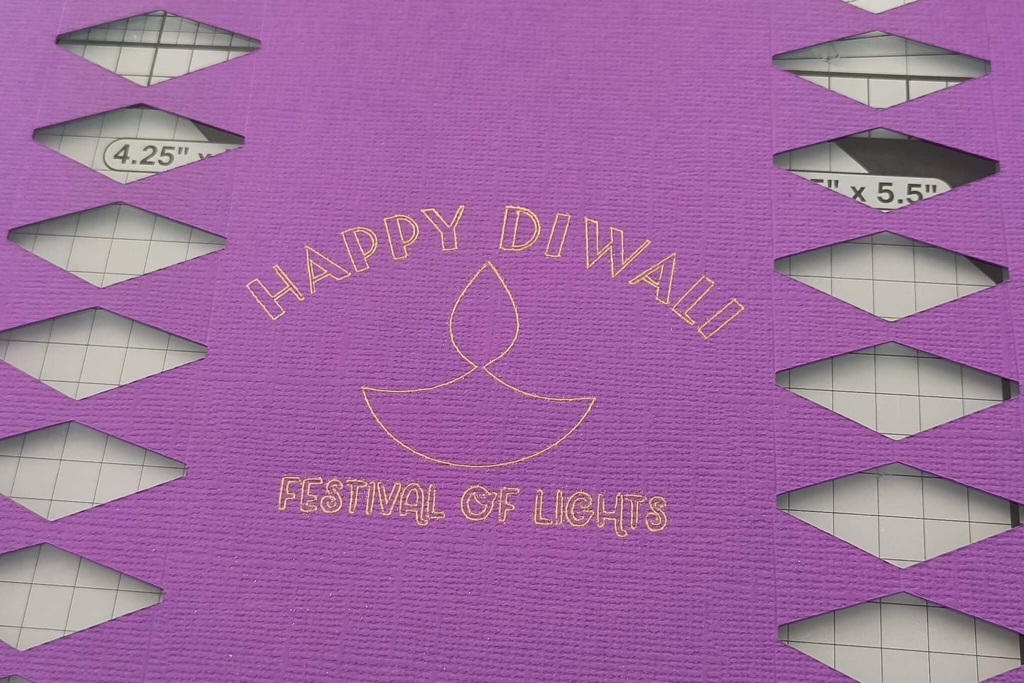 Gold foiled “Happy Diwali Festival of Lights” text with diya motif on textured purple cracker card.