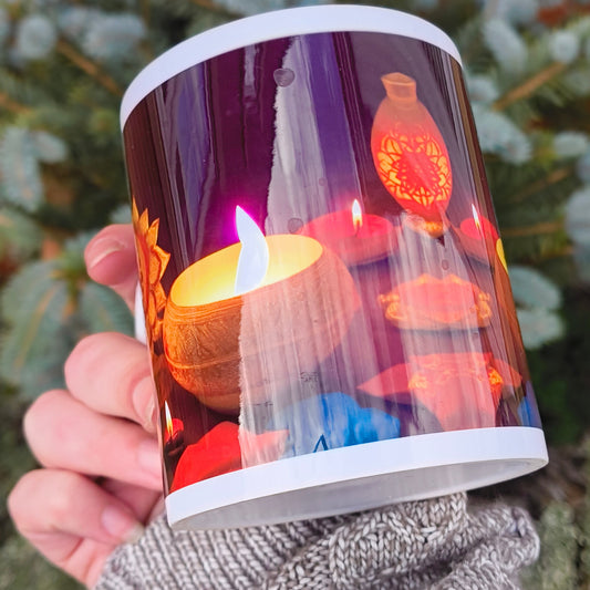Festive Diwali mug with golden mandala and glowing diyas in warm light tones, held in a cosy grey jumper against an outdoor garden background.