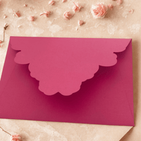 Elegant deep pink scalloped envelope perfect for Diwali gifting, adorned with delicate flowers on a textured background.