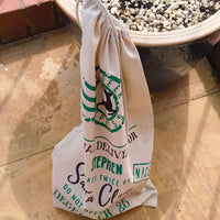 Side view of personalised Santa gift sack tied with drawstring, featuring festive Reindeer Express design in green and black lettering.
