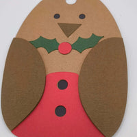 Close-up of festive robin-shaped Christmas gift tag with red belly and holly decoration.