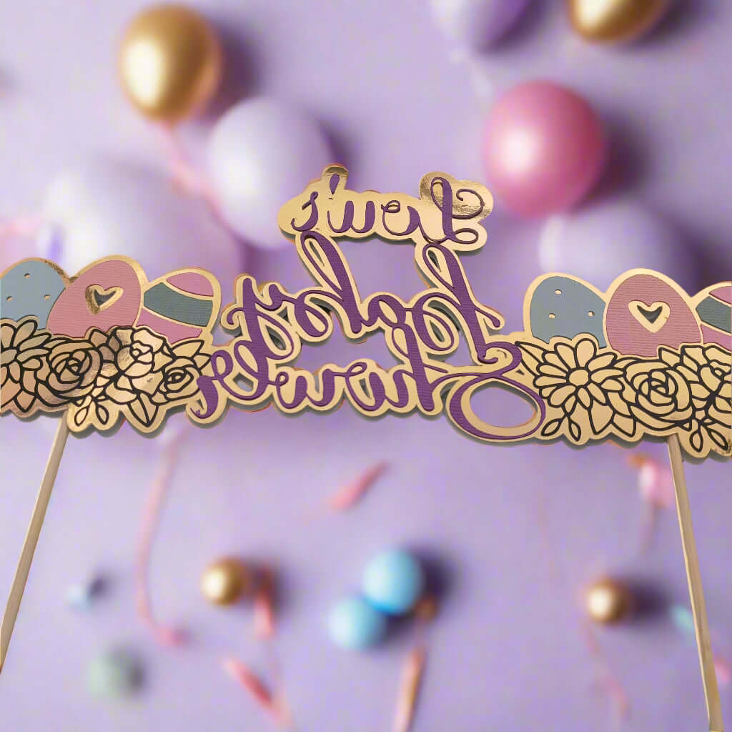 Mirrored gold and purple baby shower topper reading 'Lou's Baby Shower', surrounded by floral and baby-themed icons. The topper is set against a soft lavender background with pastel and gold balloons and ribbon decorations, creating a festive and dreamy atmosphere.