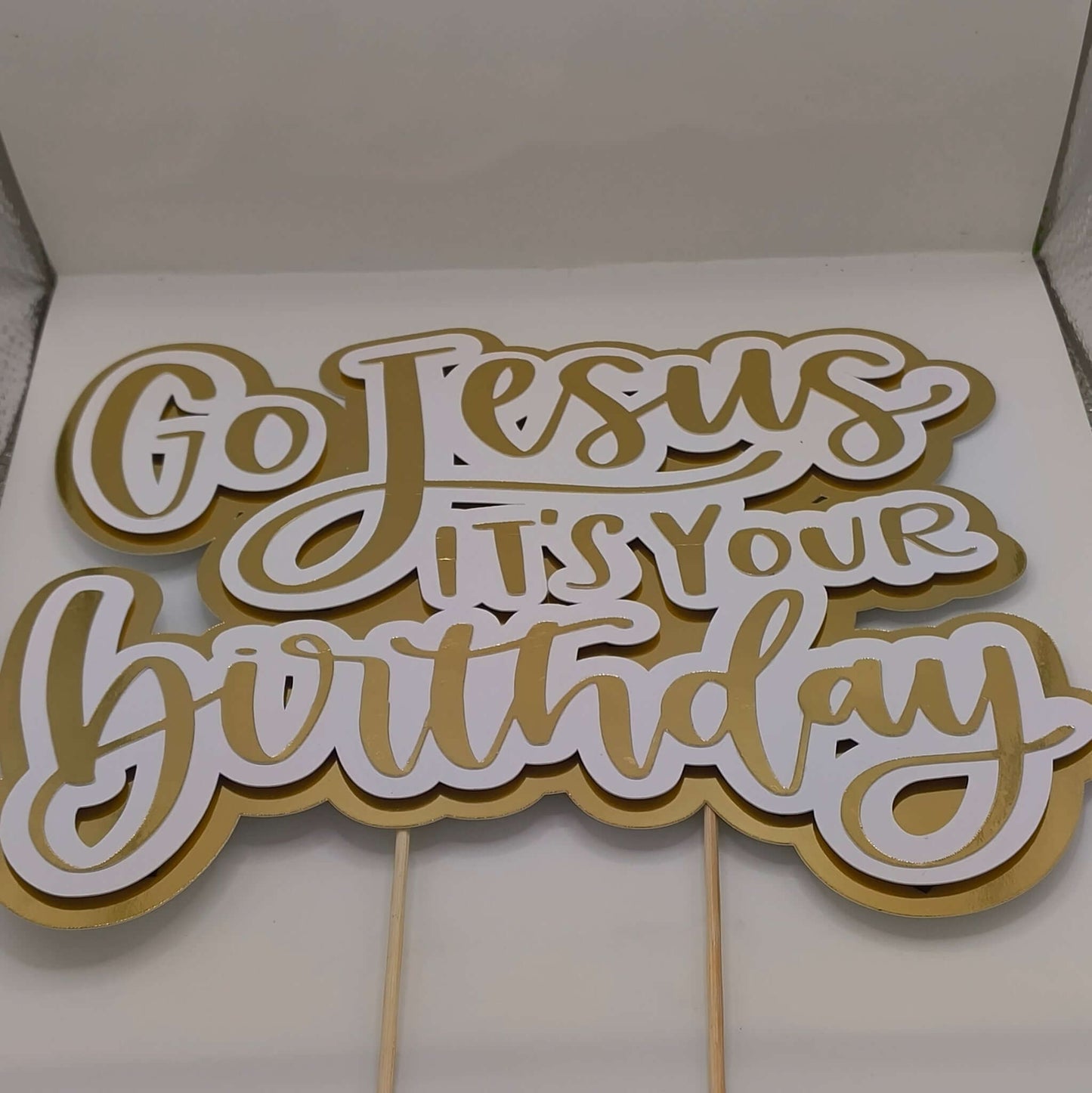 Gold and white “Go Jesus It’s Your Birthday” cake topper with wooden sticks, handmade religious party decoration.