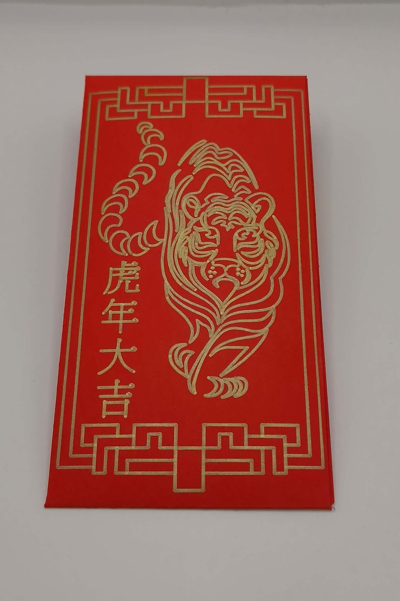 Red money envelope with full tiger illustration and Chinese characters drawn in gold pen