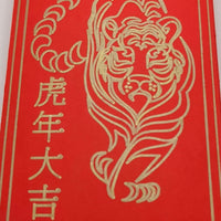Close-up of tiger illustration in gold pen on red Chinese New Year envelope.